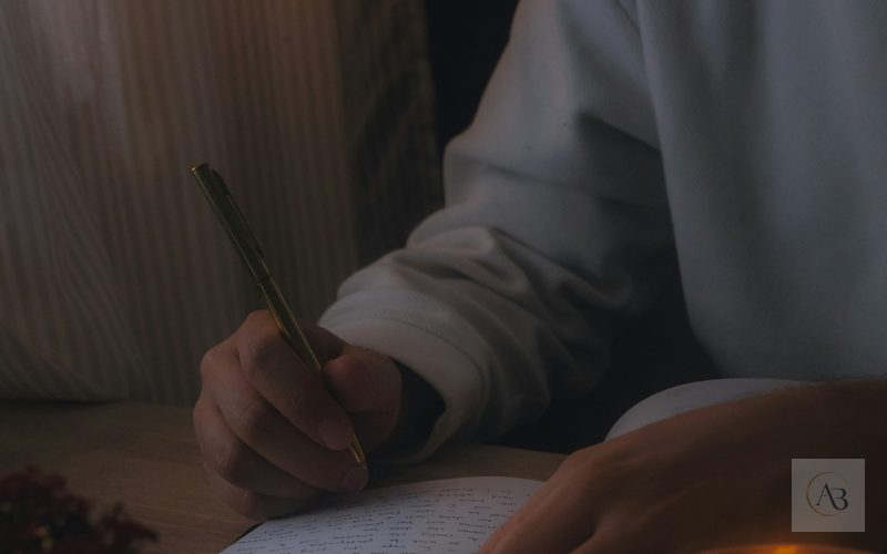 Persona escribiendo en un cuaderno en penumbra como símbolo de observar pensamientos, emociones y conducta