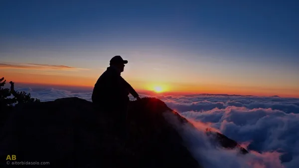 Silueta de persona en roca al atardecer — usar el dolor como palanca de cambio